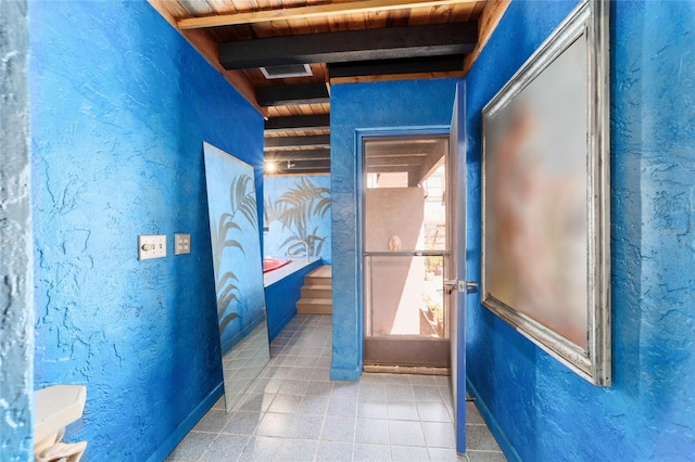 interior space with wooden ceiling, tile patterned floors, beam ceiling, and a textured wall