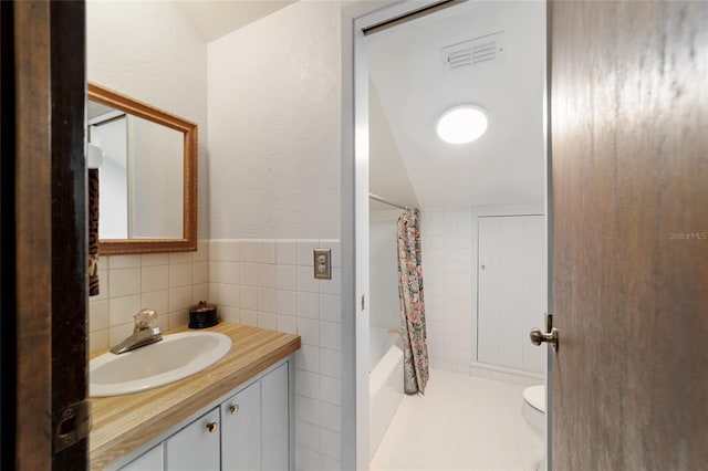 full bathroom with tile walls, visible vents, toilet, shower / bath combo, and vanity