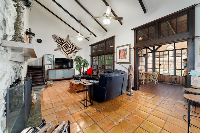 living area featuring a ceiling fan, stairs, a fireplace, high vaulted ceiling, and beam ceiling