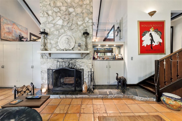 living room featuring a high ceiling, stairway, a fireplace, and stone tile floors