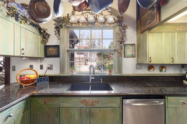 kitchen with green cabinets, stainless steel dishwasher, dark stone countertops, and a sink