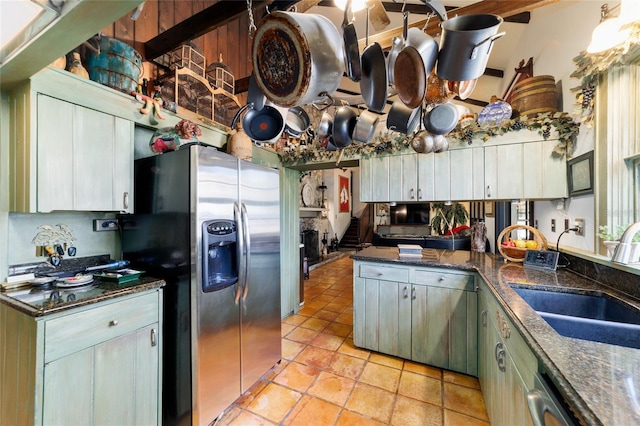 kitchen featuring dark stone counters, appliances with stainless steel finishes, light tile patterned floors, and a sink