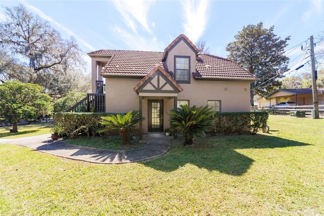 view of front of home featuring a tiled roof, a front lawn, and stucco siding