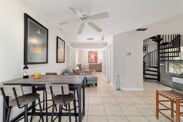 dining room featuring light tile patterned floors, visible vents, baseboards, french doors, and stairway