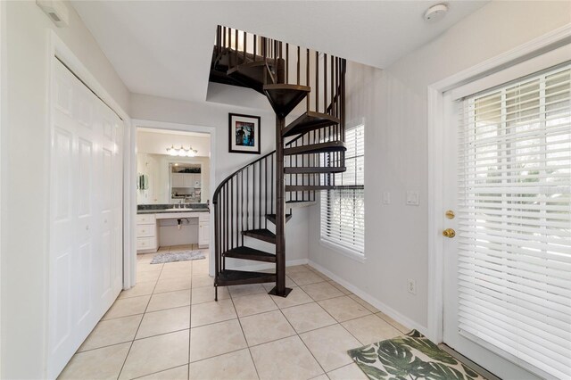 entrance foyer with light tile patterned floors, stairs, and baseboards