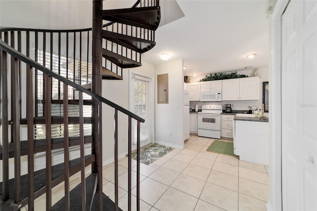 interior space featuring light tile patterned flooring, white appliances, white cabinetry, baseboards, and dark countertops