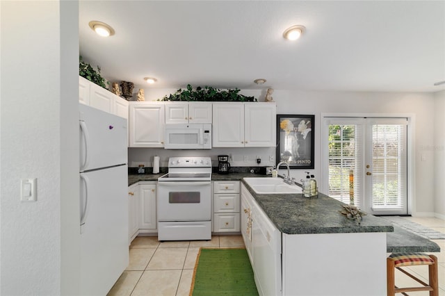 kitchen with dark countertops, white appliances, a sink, and a peninsula