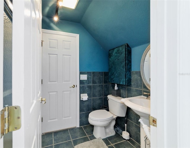 bathroom with lofted ceiling, tile walls, toilet, and tile patterned floors