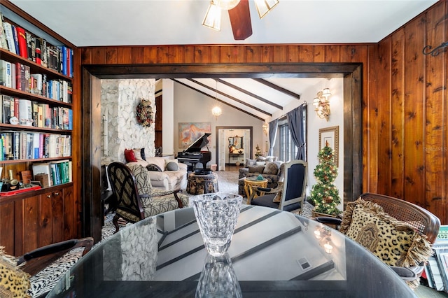 interior space featuring a ceiling fan, lofted ceiling, and wooden walls