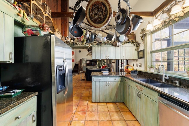 kitchen with light tile patterned floors, stainless steel appliances, dark stone counters, and a sink