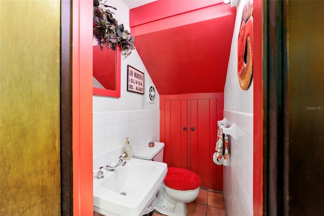 bathroom featuring tile patterned flooring, a sink, tile walls, and toilet