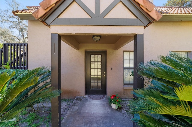 entrance to property featuring a tiled roof and stucco siding