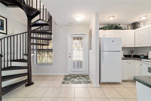 kitchen featuring freestanding refrigerator, white cabinets, dark countertops, and light tile patterned floors