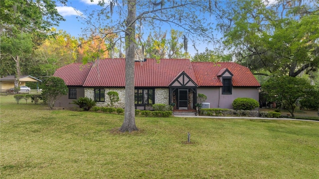 view of front of property featuring stone siding, a tile roof, stucco siding, and a front lawn