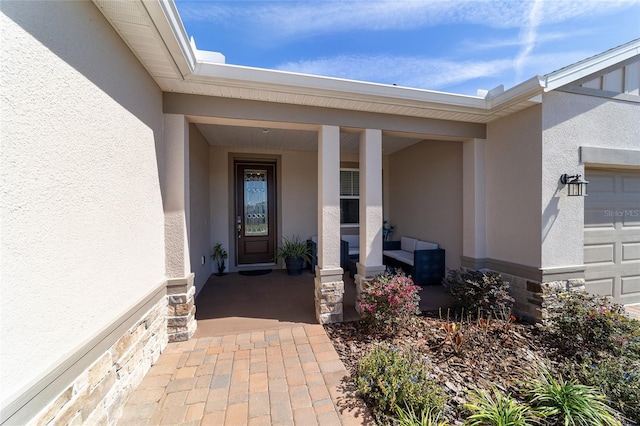 entrance to property with a porch, an attached garage, and stucco siding