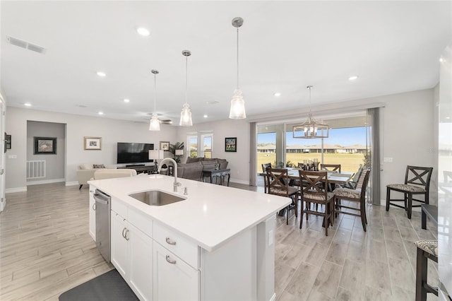 kitchen with wood finish floors, a sink, visible vents, dishwasher, and a center island with sink