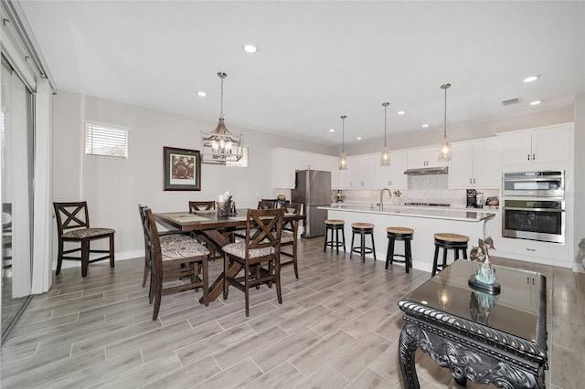 dining room featuring wood finish floors, recessed lighting, visible vents, and an inviting chandelier