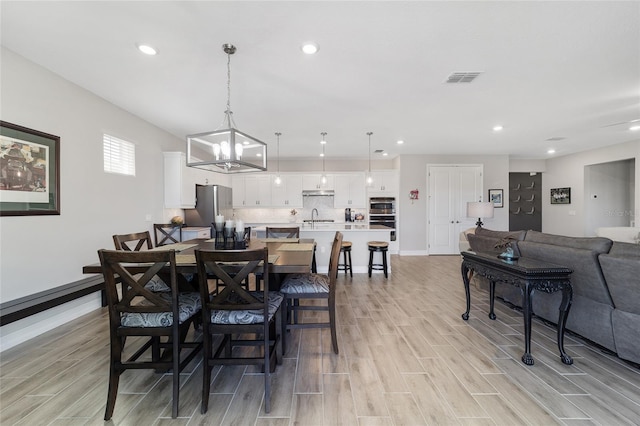 dining space featuring an inviting chandelier, wood tiled floor, visible vents, and recessed lighting