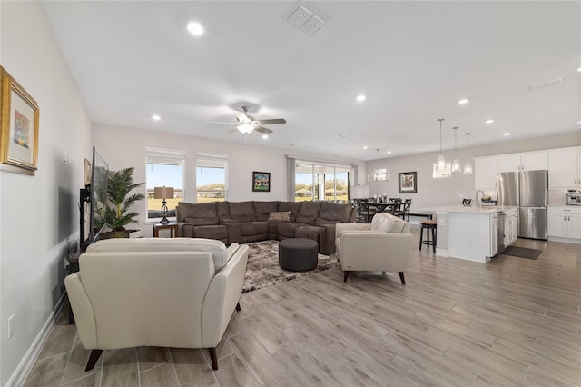 living room featuring light wood-type flooring, plenty of natural light, visible vents, and recessed lighting