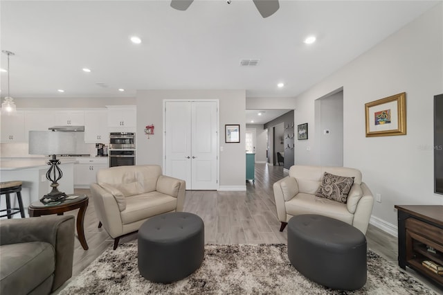 living area with baseboards, light wood-type flooring, visible vents, and recessed lighting