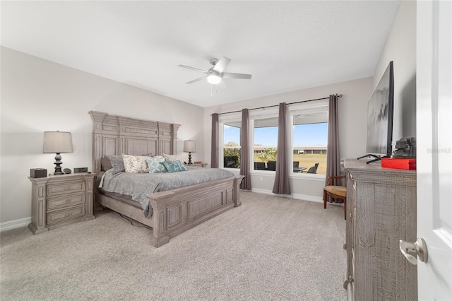 bedroom featuring light colored carpet, ceiling fan, and baseboards