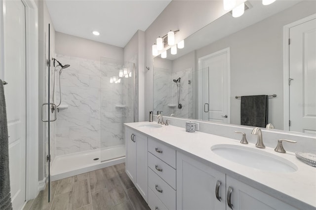 full bath featuring double vanity, a sink, and a marble finish shower