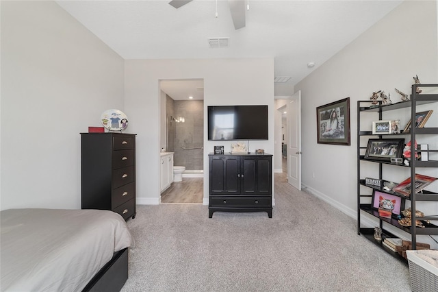 bedroom featuring baseboards, ensuite bathroom, visible vents, and light colored carpet