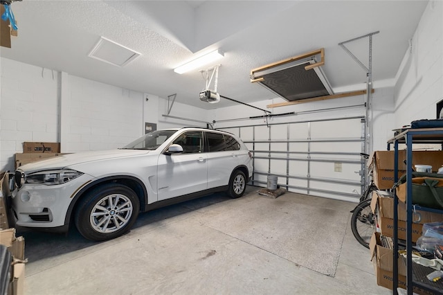 garage featuring concrete block wall and a garage door opener