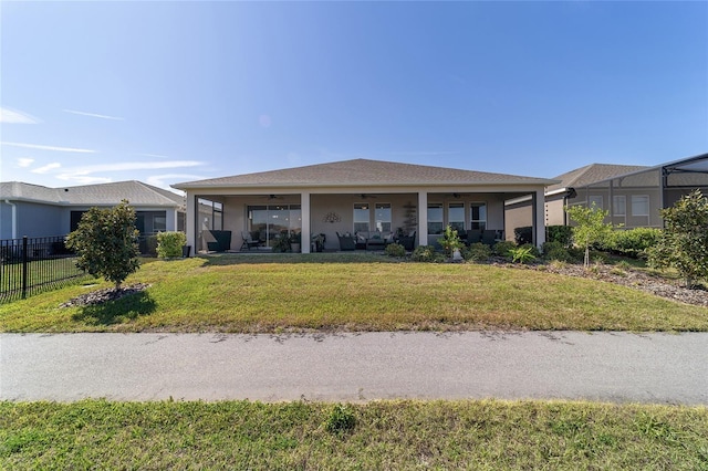 view of front of home featuring a front yard, stucco siding, fence, and ceiling fan