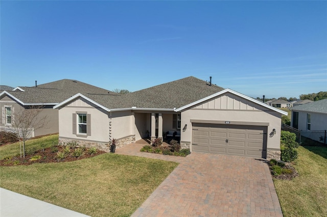 ranch-style home with a garage, stone siding, a front lawn, and decorative driveway