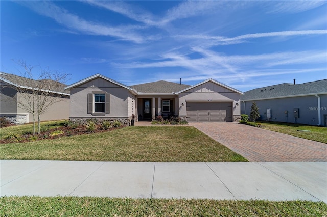 ranch-style house with decorative driveway, stucco siding, an attached garage, a front yard, and stone siding