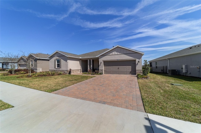 single story home with a garage, decorative driveway, cooling unit, a front lawn, and stucco siding