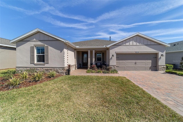 single story home featuring a garage, stone siding, a front lawn, and decorative driveway