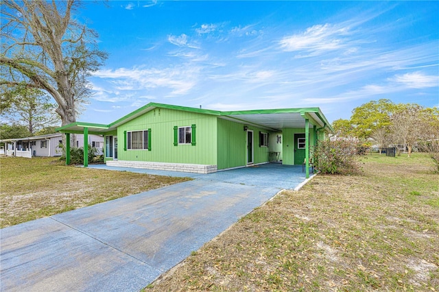 manufactured / mobile home with aphalt driveway, an attached carport, and a front lawn