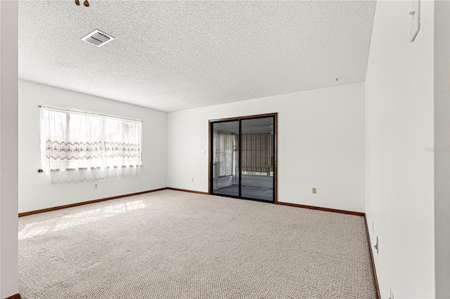 carpeted empty room featuring visible vents, a textured ceiling, and baseboards