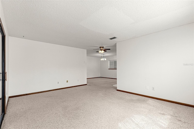 carpeted empty room featuring a ceiling fan, visible vents, a textured ceiling, and baseboards