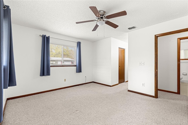 spare room featuring a textured ceiling, carpet floors, visible vents, and baseboards