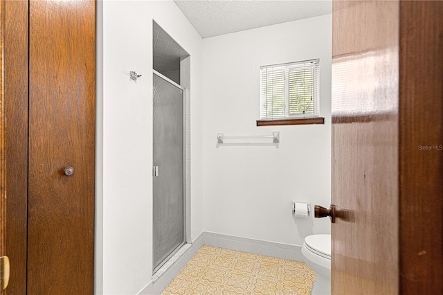 full bath with a textured ceiling, tile patterned flooring, toilet, baseboards, and a stall shower