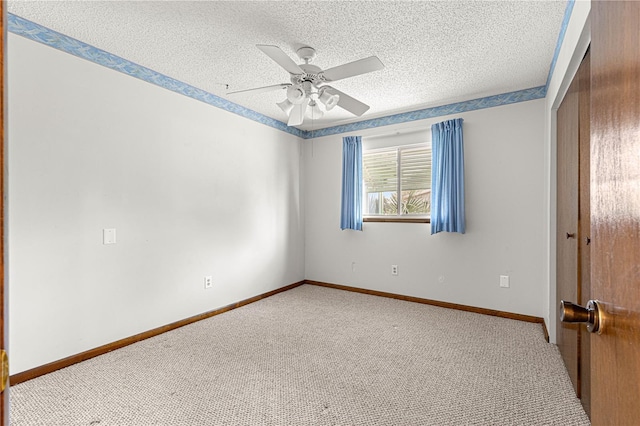 carpeted empty room with a textured ceiling, a ceiling fan, and baseboards