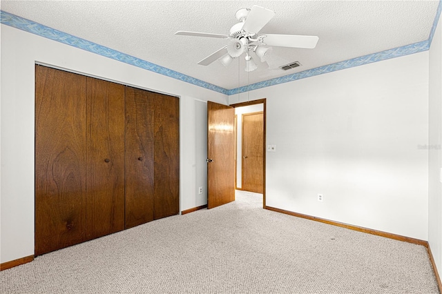 unfurnished bedroom featuring a textured ceiling, carpet floors, visible vents, baseboards, and a closet