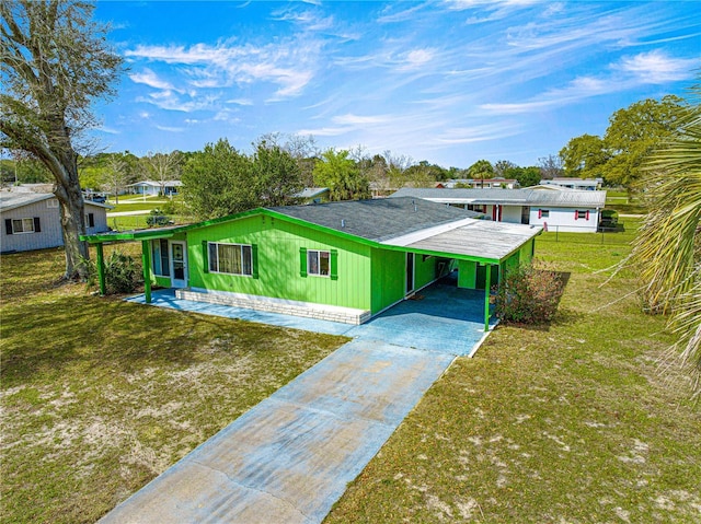 view of front facade with an attached carport, concrete driveway, and a front lawn