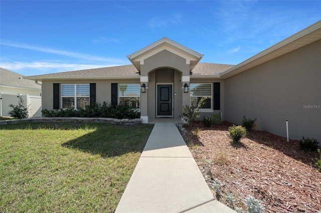 view of front of property with a front yard, fence, and stucco siding