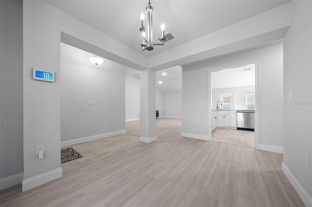 unfurnished dining area featuring baseboards, visible vents, a notable chandelier, light wood-style floors, and a sink