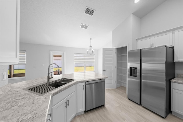 kitchen featuring lofted ceiling, stainless steel appliances, a sink, and visible vents