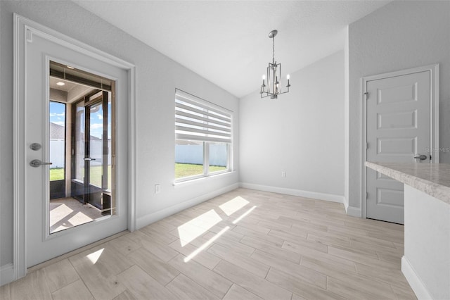 unfurnished dining area with lofted ceiling, wood finish floors, a notable chandelier, and baseboards