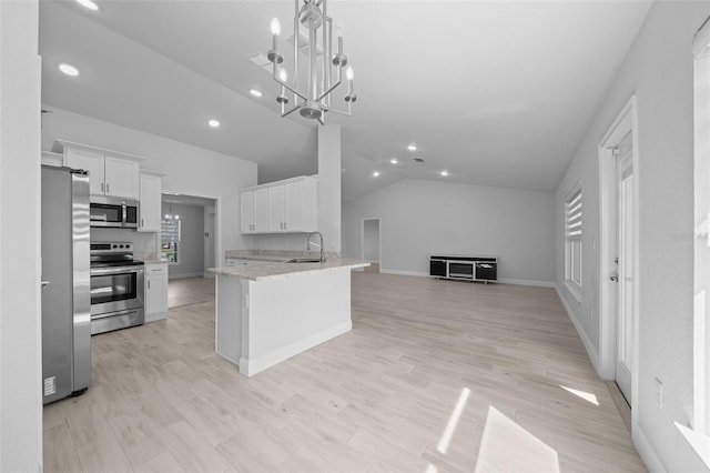 kitchen with a sink, white cabinetry, open floor plan, appliances with stainless steel finishes, and an inviting chandelier