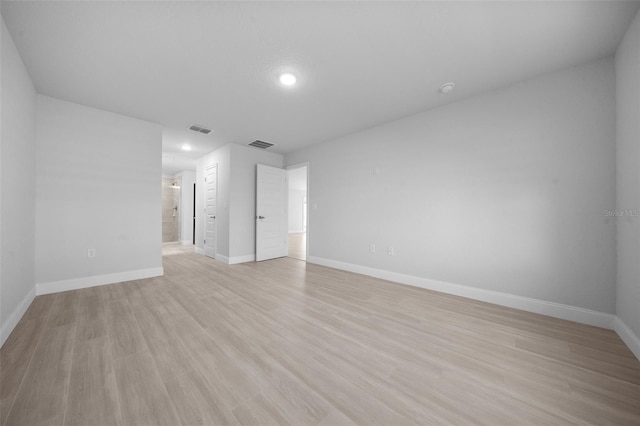 spare room featuring light wood-style flooring, visible vents, and baseboards