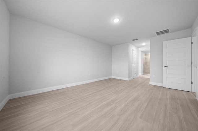 empty room featuring visible vents, light wood-style flooring, and baseboards