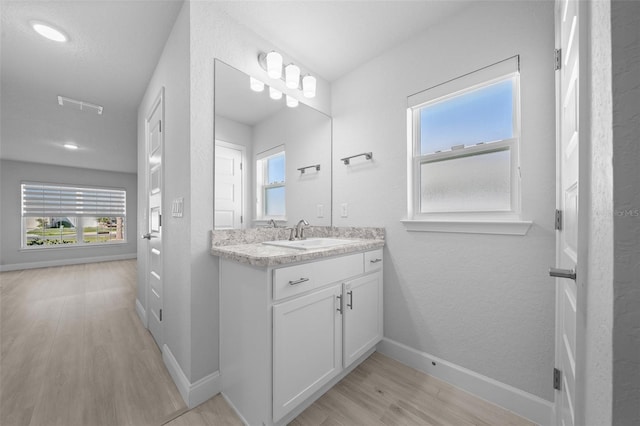 bathroom featuring plenty of natural light, baseboards, wood finished floors, and vanity