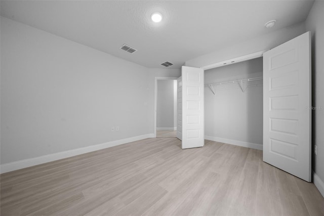 unfurnished bedroom with light wood finished floors, visible vents, and baseboards